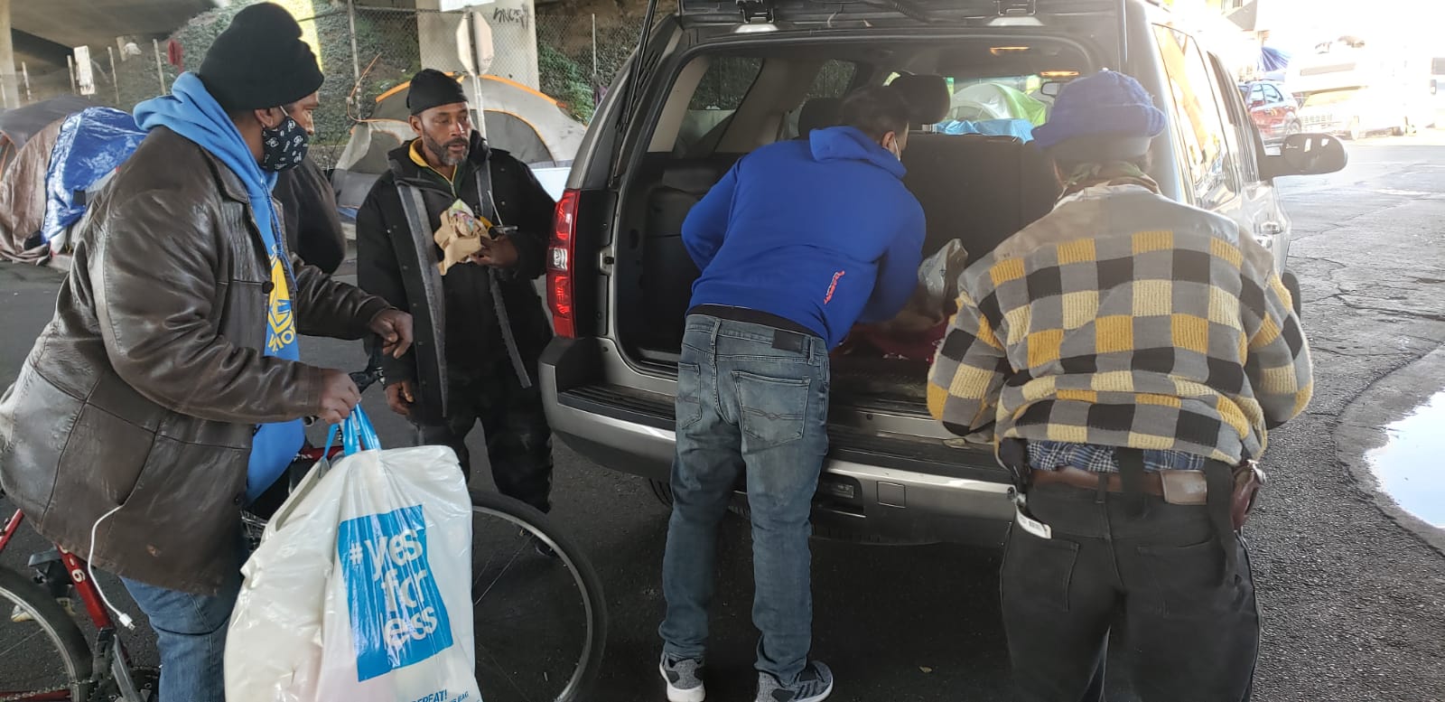 People sharing bags of supplies near a vehicle